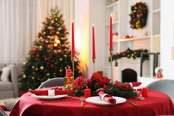 Stylish Christmas table setting with plates, festive decor and burning candles indoors
