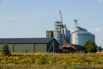 Granary and silos stand tall in a farming area, used for storing grain and agricultural products, with machinery near a warehouse