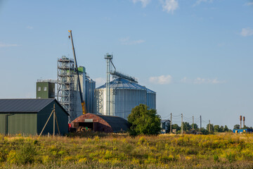 Large silos and a granary sit in a rural area, reflecting the importance of grain storage in modern farming. A crane is visible in the background