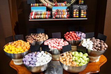 Colorful French macarons in metal bowls on display at a pastry shop
