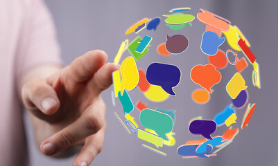 Concept of communication, global network, and sharing ideas. Hand reaching out to a sphere of colourful speech bubbles, representing conversatio