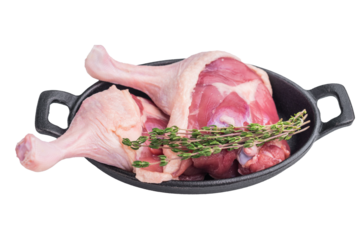 Raw duck legs and thighs placed in a black cast iron skillet, garnished with fresh thyme sprigs — a stylish culinary presentation.