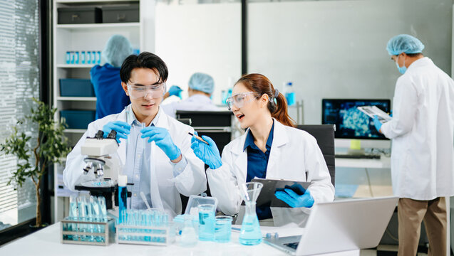 Team of scientists analyzing blue liquid samples in a modern lab, showcasing biotechnology, chemistry, and medical research innovation.