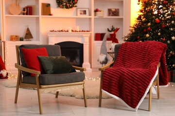 Fireplace, armchairs, Christmas tree and festive decor in stylish room