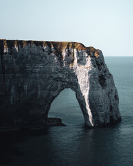 Impressive natural rock arch standing tall above calm sea waters during bright daylight
