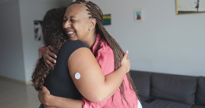 African mother hugging her daughter with diabetes patch - Family, lifestyle and people diseases concept