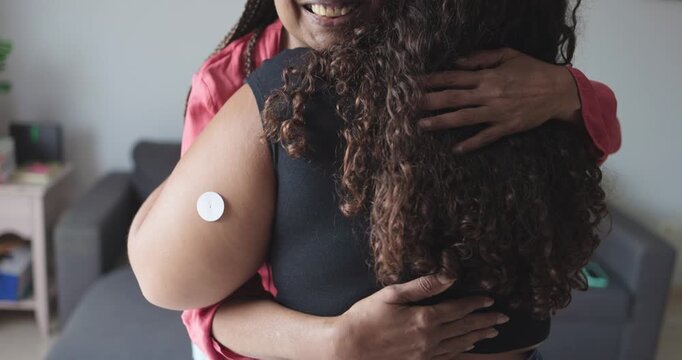 African mother hugging her daughter with diabetes patch - Family, lifestyle and people diseases concept