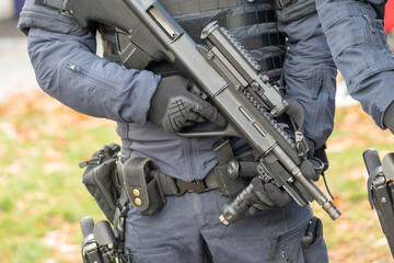 A policeman is in gear and holding a large tactical weapon.