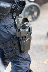 A policeman stands on the street with a holster on his hip