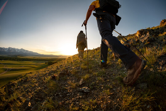 Silhouettes of hikers couple are walking in sunset mountains. Active summer vacations concept