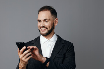 Portrait of a professional man in a business setting, smiling while looking at a smartphone. The isolated colored background highlights a confident, engaged mood.
