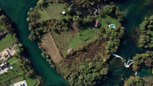 Drone footage showing a closer aerial view of the heart shaped bend of the Una River near Bihac, Bosnia and Herzegovina. Clear turquoise water, green nature, and small waterfalls captured from above.