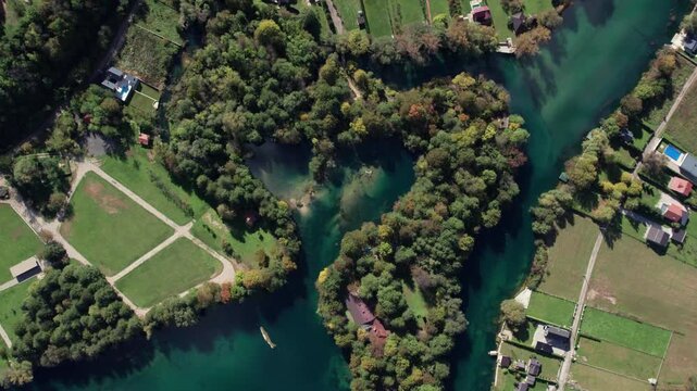 Cinematic aerial footage of the Una River forming a heart shape near Bihac japodski otoci, Bosnia and Herzegovina. Clear turquoise water, green forest, and countryside landscape captured from a drone.