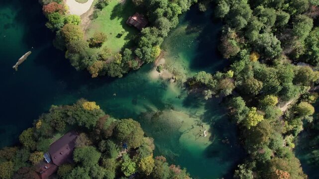 Drone footage of the Una River forming a natural heart shape near Bihac japodski otoci, Bosnia and Herzegovina. Clear turquoise water surrounded by green forest captured from above on a sunny day.