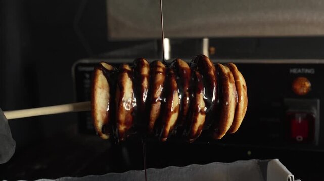 Man chef put chocolate syrup on delicious mini pancakes in the box