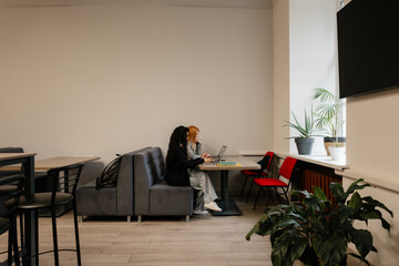 Casual office lounge scene showing collaboration and focus in a bright, plant-filled coworking area.