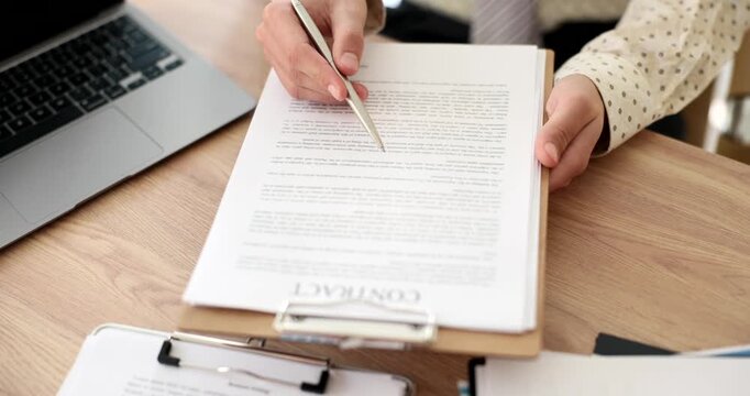 Experienced businesswoman presents contract to partner for review. Businessman sits at desk and studies obligations and terms with attention to detail