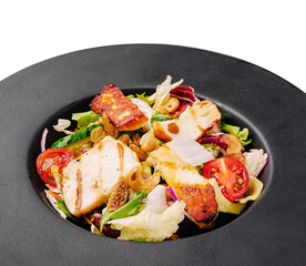Fresh salad with grilled chicken, nuts, and vegetables served on a dark plate