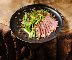 Fresh salad with sliced meat and dried fruits on a wooden table
