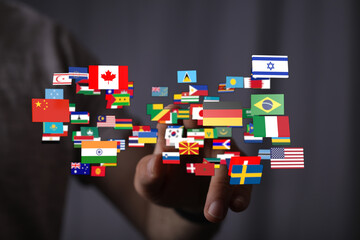 A hand interacting with a 3D rendered display showcasing diverse national flags, symbolizing global...