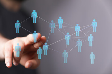 Hand reaching towards a network of connected human icons symbolizing connection, communication, and business co