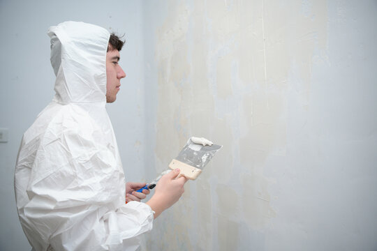 Man plastering wall wearing protective suit for home improvement