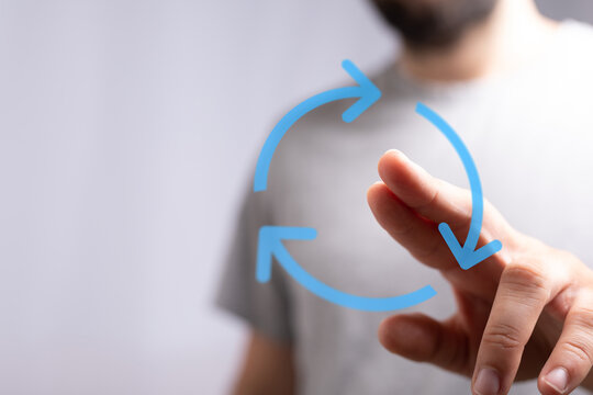 Hand pointing towards a blue circular arrow on a transparent interface. Concept of renewal, recycling, and sustainable development. - Powered by Adobe