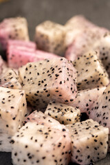 diced ripe red pitaya with lots of small black seeds and white soft sweet flesh inside, sweet dragon fruit with black small seeds and light flesh cut in half into small cubes