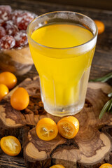 Fototapeta premium citrus-flavored orange juice and fruits on a wooden table, delicious and fresh orange juice and fresh kumquat fruits next to a glass