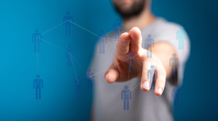 Close up of a man's hand touching a network of digital human figures against a blue background, representing co