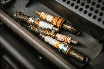Old spark plugs lying on engine needing replacement