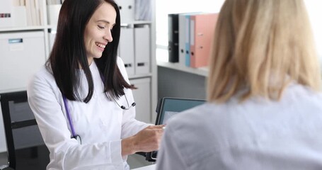 Woman doctor shows chest X-ray on tablet to woman patient in office. Female doctor points to shadow and explains risk proposing test at appointment - Powered by Adobe