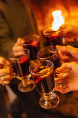 Close-up of the women saying a toast and clinking glasses with mulled wine