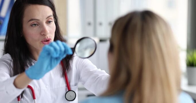 Woman doctor holds magnifier glass examining face skin of woman patient. Doctor checks pores and maps spots explaining care steps for treatment