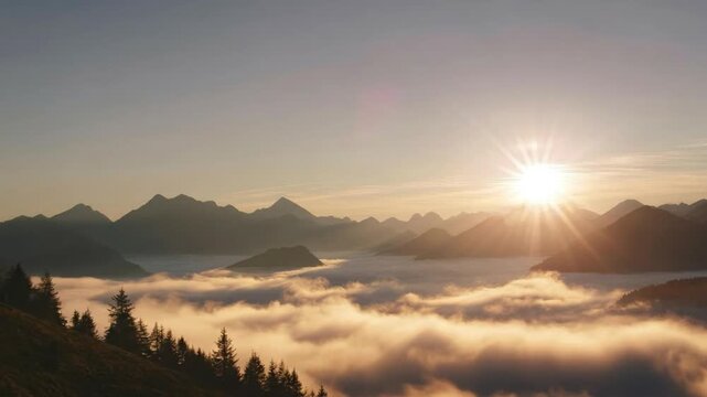 This breathtaking aerial perspective captures a majestic mountain range at sunrise, with the golden sun bursting over distant peaks and casting a warm, radiant glow across a tranquil sea of rolling cl