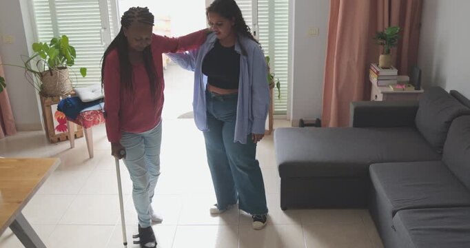 African american daughter helping her mother to wear a foot brace after a injury - Medical, insurance and health care concept
