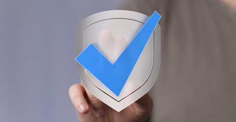 Hand holding a digital shield icon with a blue checkmark, symbolizing validation, confirmation, and...