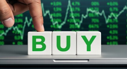 Finger pressing on the word BUY displayed on wooden blocks concept for stock market investment and financial decisions