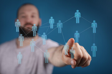 Close-up of a man's finger interacting with a network of digital human figures. Illustrates connection, communication, and technological advance