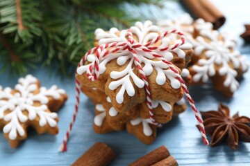 Tasty gingerbread cookies, spices and fir tree branches on light blue wooden background, closeup. Christmas treat