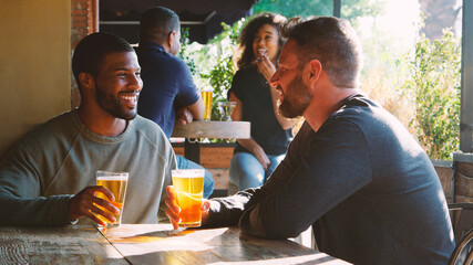 Two Male Friends Meeting In Bar Enjoying Drink Together