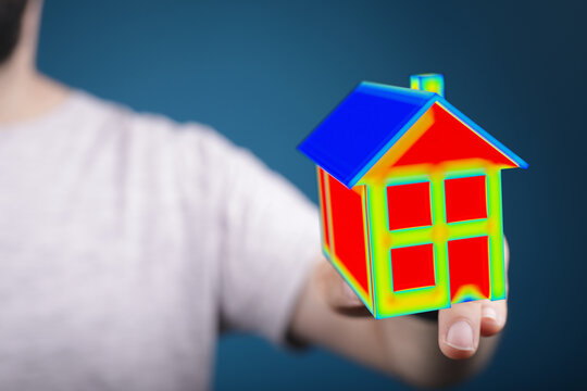 Conceptual image of a person presenting a house model with heat map representing energy efficiency. Ideal for illustrating concepts related to h