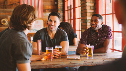 Group Of Male Friends Meeting And Drinking Beer In Sports Bar Together