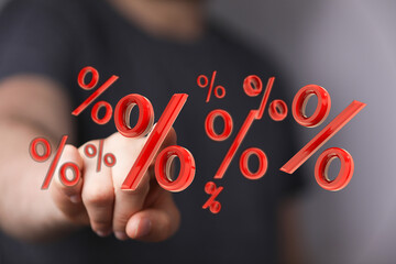 Close-up of a hand pointing at floating percentage symbols representing discounts, savings, and financial concepts like investment returns and m