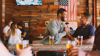Two Male Friends Meeting In Sports Bar Enjoying Drink Before Game