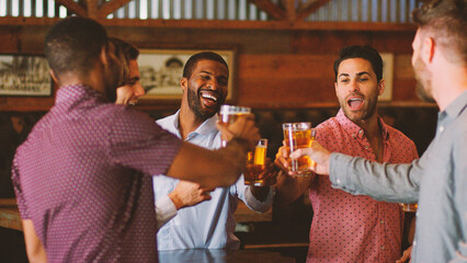 Group Of Male Friends On Night Out For Bachelor Party In Bar Making Toast Together