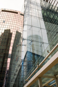 Tall modern architecture with overlapping glass planes, precise facade geometry and reflective corporate tower detail shaping an urban structure in La Defense, Paris