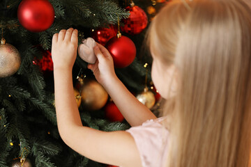 Little girl decorating Christmas tree at home, closeup