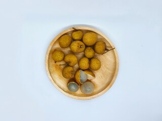 Fresh Tropical Longan Fruits on a Wooden Plate Against a White Background