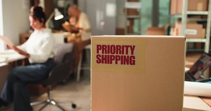 Priority shipping label, box and logistics office for ecommerce, supply chain or distribution. Package, startup or express delivery service with important parcel, sticker or team of business people